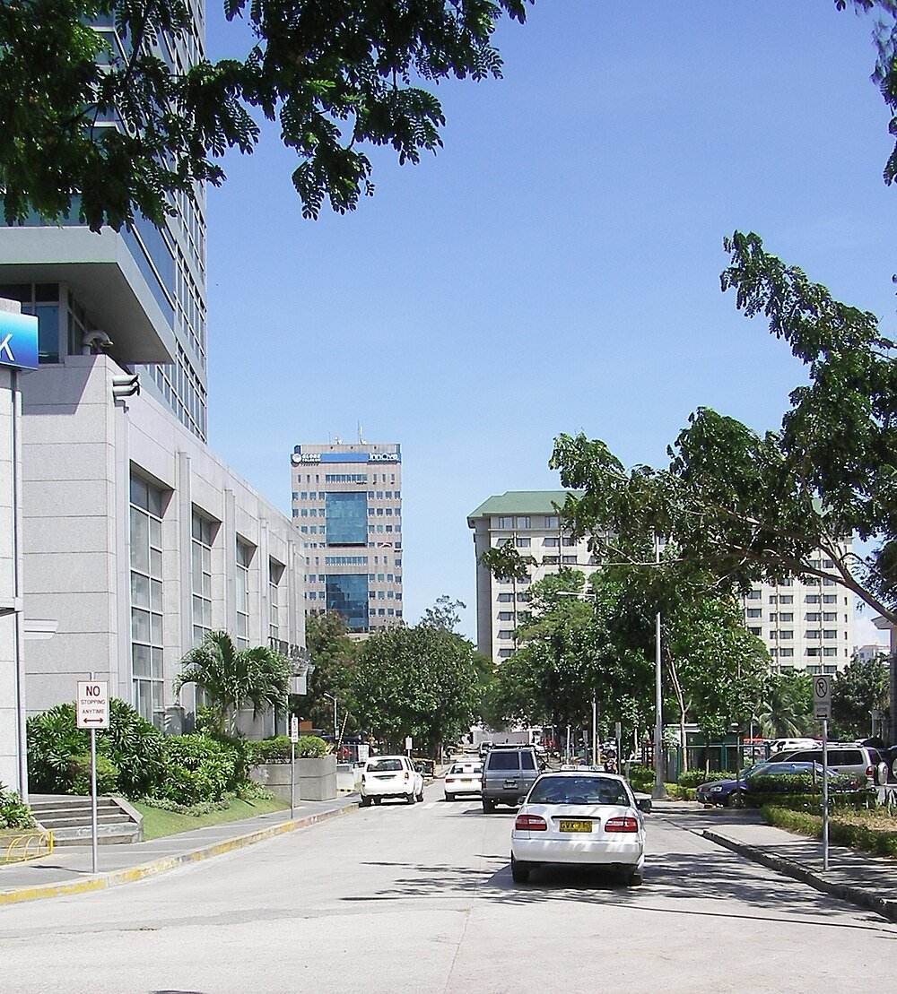 Urban street with cars and office buildings Urban street scene with cars, trees, and modern office buildings under clear blue sky