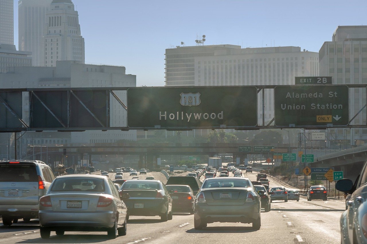 Busy highway traffic on US Route 101 heading towards Hollywood with city buildings and exit signs in Los Angeles