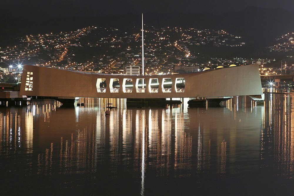 USS Arizona Memorial at Pearl Harbor at Night Night view of the USS Arizona Memorial at Pearl Harbor with city lights reflecting on the water surface
