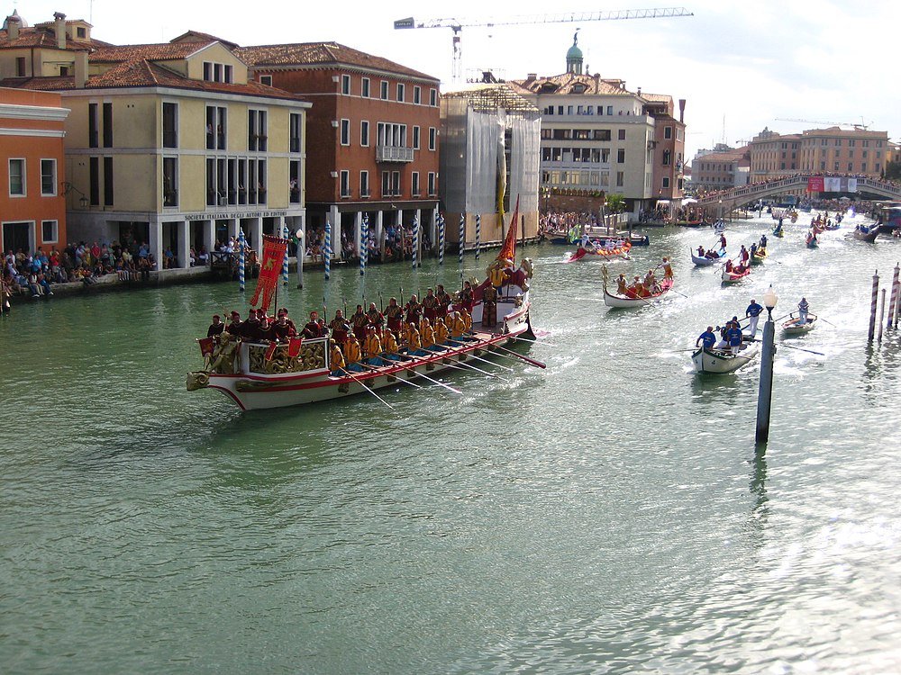 Venice canal regatta with traditional rowing boats Traditional rowing boats with rowers in colorful uniforms on a canal in Venice during a regatta event with historic buildings