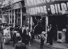 Vintage cinema entrance with crowd gathered outside Black and white photo of a crowd gathered outside a vintage cinema entrance with marquee signs and posters