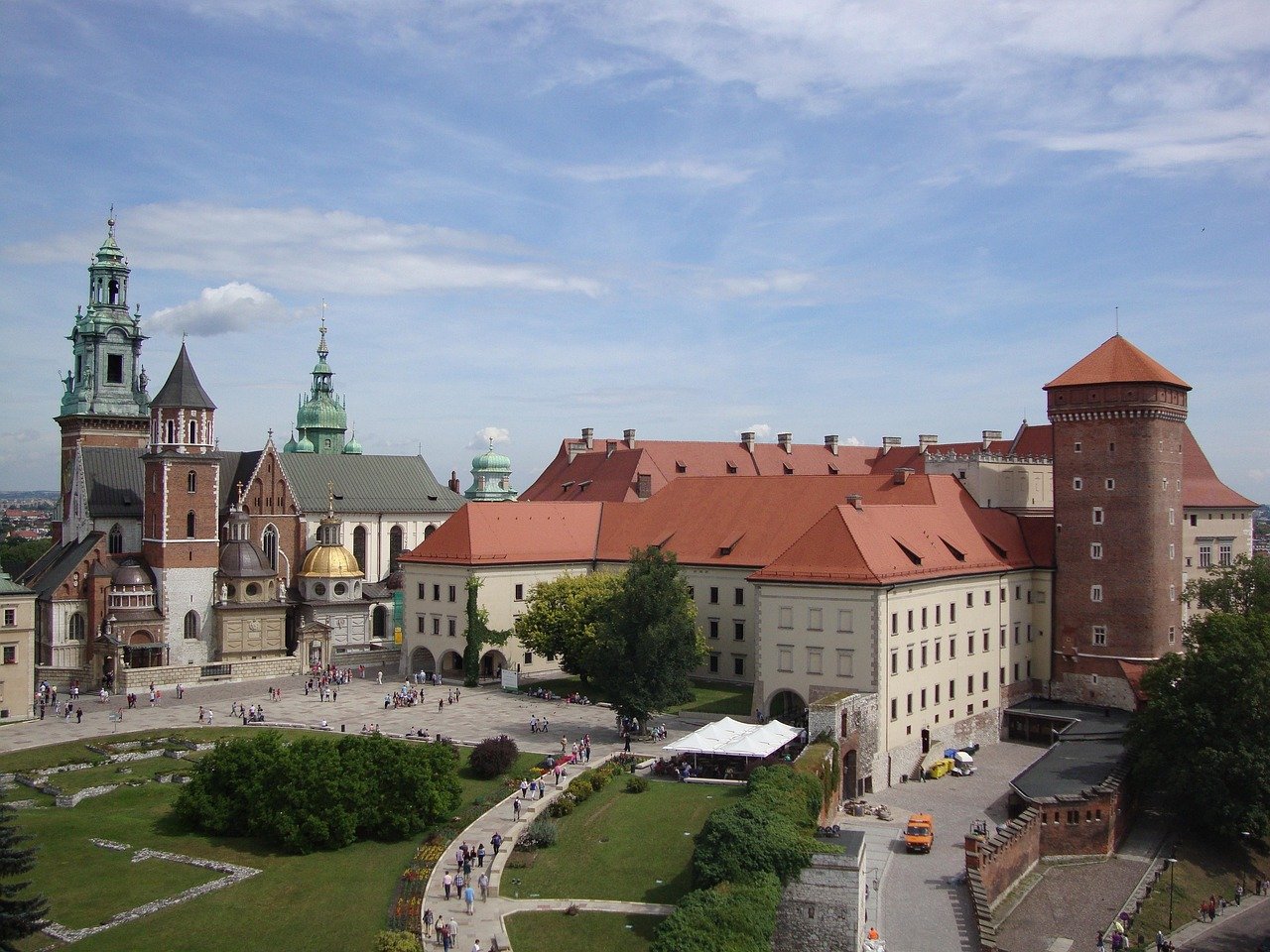 Historic Wawel Castle with red roofs and cathedral towers in Krakow, Poland, popular tourist destination with gardens and pathways.