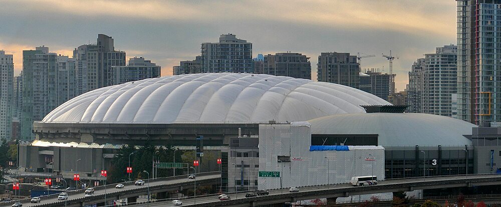 White domed stadium with city skyline and highway Large white domed stadium with city skyline and highway traffic in the foreground during sunset