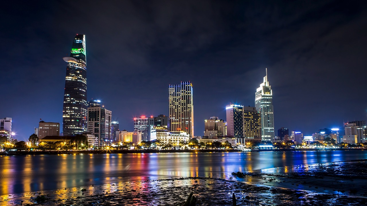 City skyline at night with colorful reflections Nighttime city skyline with illuminated skyscrapers and colorful reflections on the water in an urban waterfront area