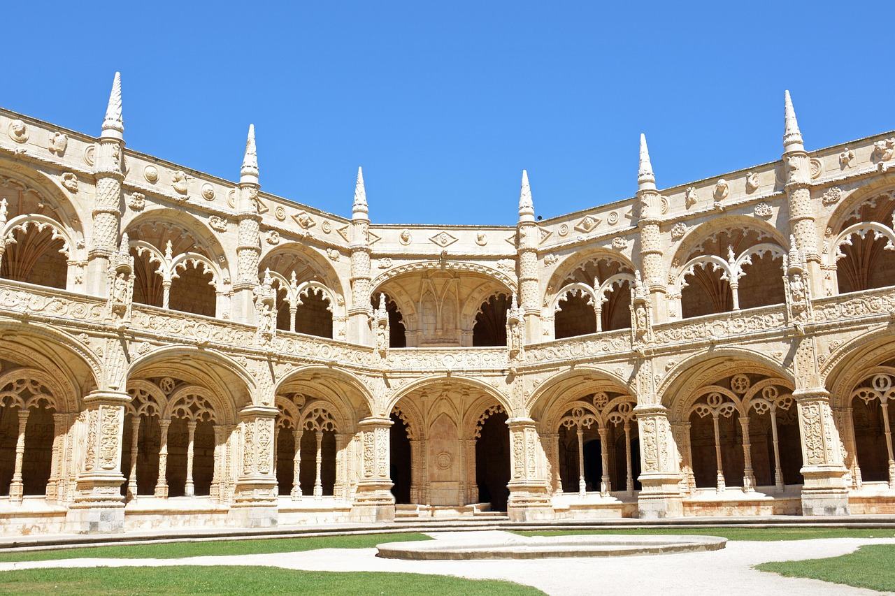 Ornate historic cloister with stone arches and spires Historic ornate cloister with detailed stone arches and spires under clear blue sky in a European monastery courtyard