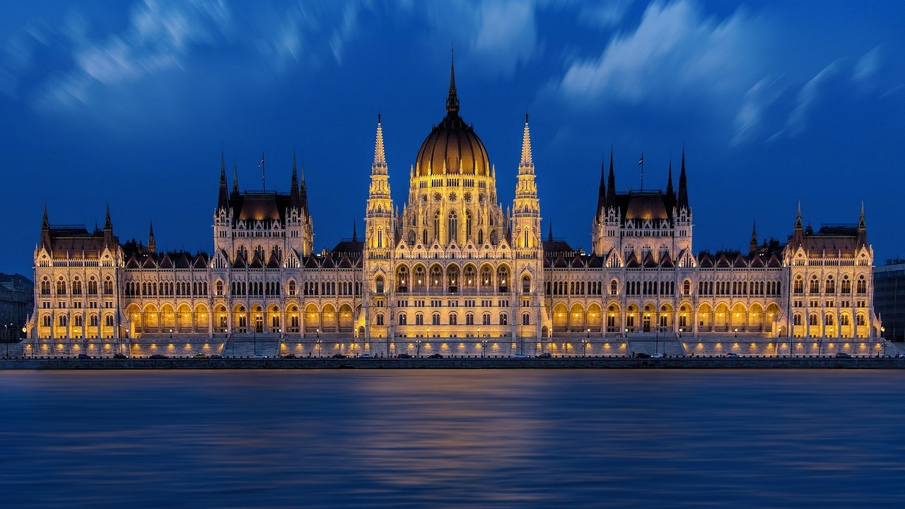 Hungarian Parliament Building at Night in Budapest Illuminated Hungarian Parliament Building at night with blue sky and Danube River in Budapest, Hungary