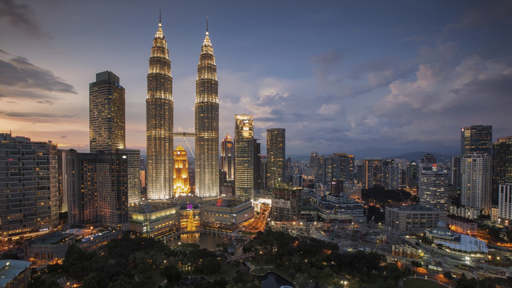 Night view of Kuala Lumpur city skyline with illuminated Petronas Twin Towers and surrounding skyscrapers