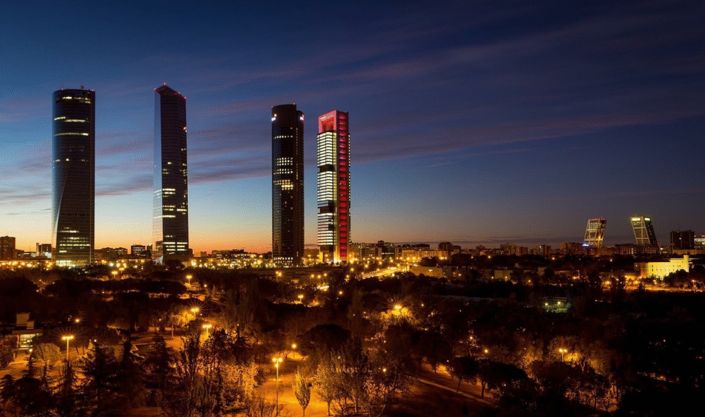 Night skyline of Madrid with the illuminated Cuatro Torres business district — Spain's modern capital seen against the dramatic Castilian-plateau sky