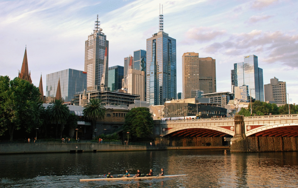 Melbourne city skyline with Yarra River, modern skyscrapers, and rowers on the water — Australia's cultural capital framed against its iconic urban riverfront