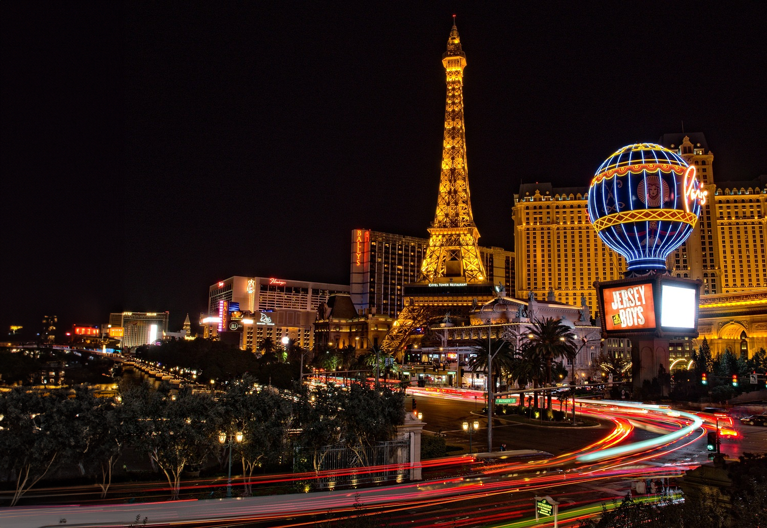 Las Vegas Strip at Night with Eiffel Tower Replica Night view of Las Vegas Strip with illuminated Eiffel Tower replica and vibrant neon signs showcasing casinos and entertainment.