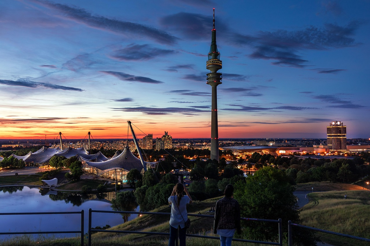 Munich cityscape with Olympic Tower at sunset Sunset view of Munich cityscape with Olympic Tower and illuminated buildings reflecting on water