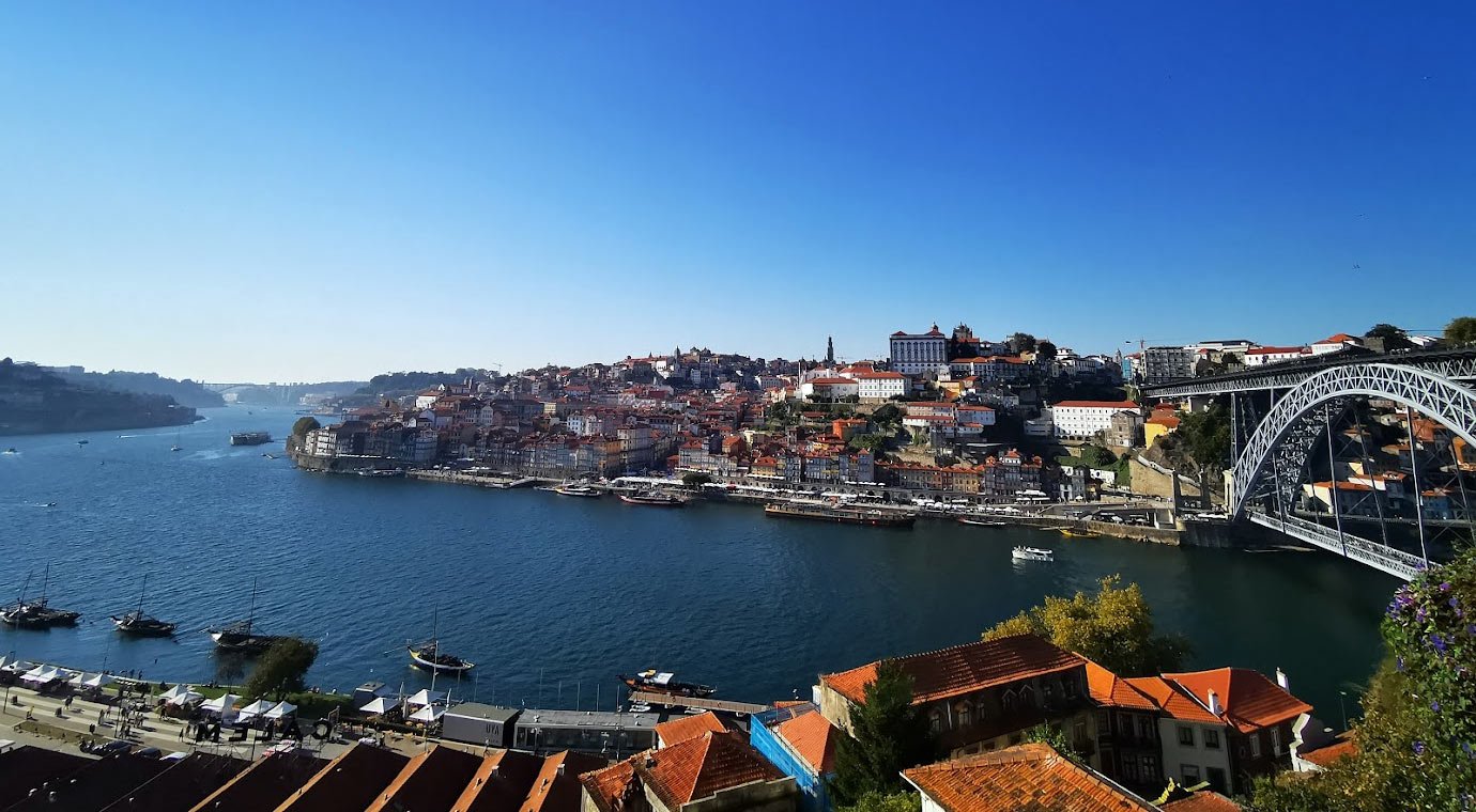 Porto cityscape with Douro River and Dom Luís I Bridge Scenic view of Porto city with Douro River, historic buildings, and Dom Luís I Bridge under clear blue sky