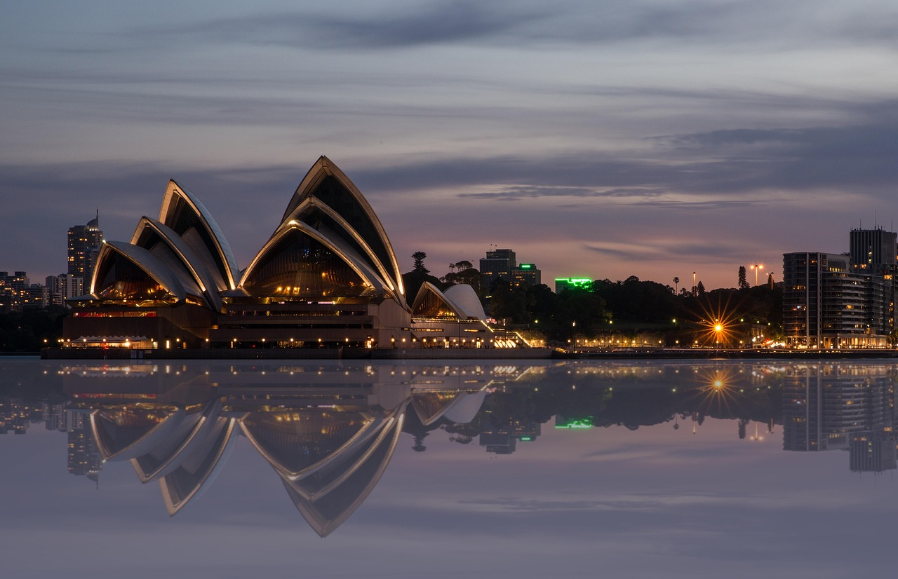 Sydney Opera House at dusk with city skyline Sydney Opera House illuminated at dusk with city skyline and water reflection in Sydney, Australia
