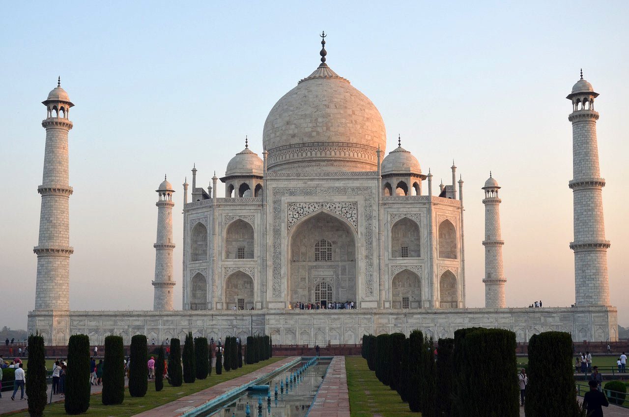 Taj Mahal White Marble Monument at Sunset The Taj Mahal in India at sunset with its iconic white marble dome and minarets, surrounded by gardens and reflecting pool