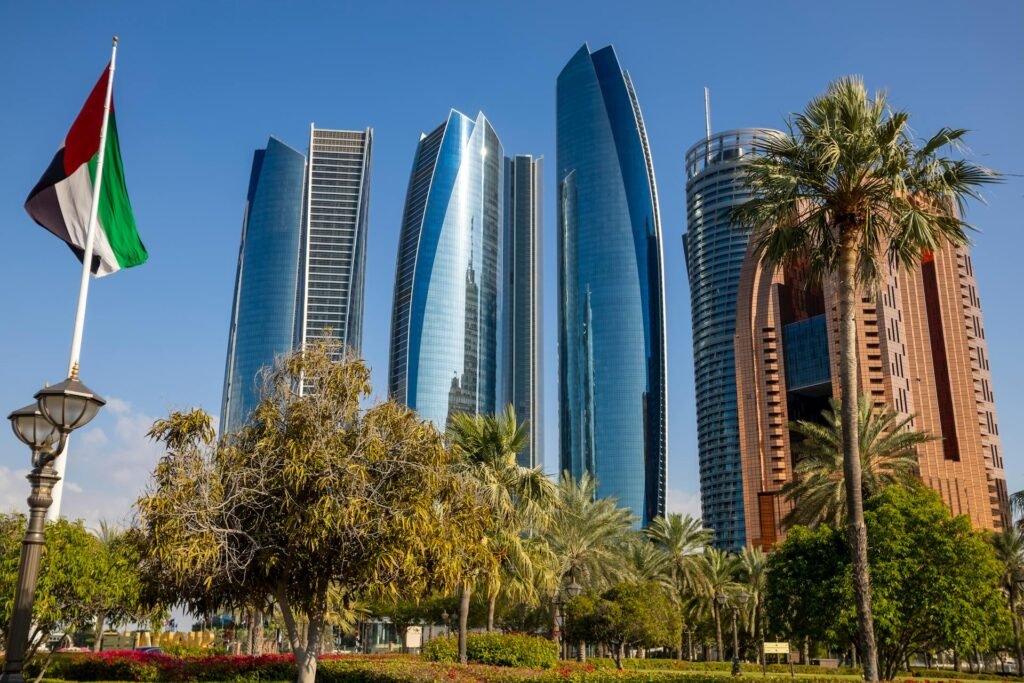 The Etihad Towers complex in Abu Dhabi — five 270-meter-plus skyscrapers with palm trees and the UAE flag in the foreground, framing the city's modern luxury skyline