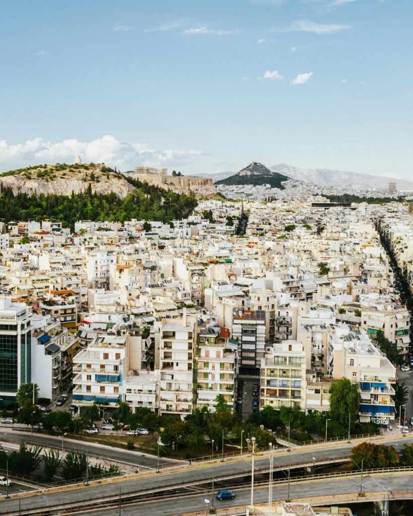 Stunning aerial view of Athens showcasing the Acropolis and the surrounding urban landscape under a clear blue sky — the modern Greek capital framed by Mount Lycabettus and the Attic plain
