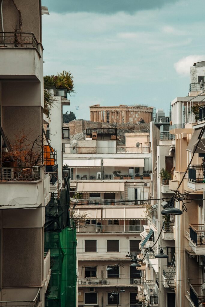 Street-level perspective in central Athens blending ancient ruins with contemporary architecture — the layered urban fabric of the Plaka and Monastiraki districts where the city's classical, Byzantine, Ottoman, and modern eras coexist