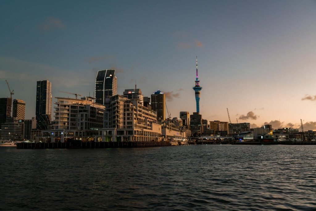 Captivating view of Auckland's skyline featuring the iconic 328-meter Sky Tower at dusk — the Southern Hemisphere's tallest structure rising above the Waitematā Harbour