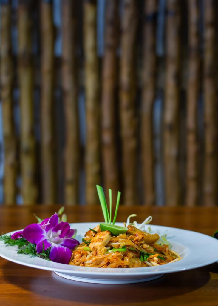 A close-up of authentic Thai pad thai with shrimp, peanuts, and an orchid garnish — Bangkok's signature street dish