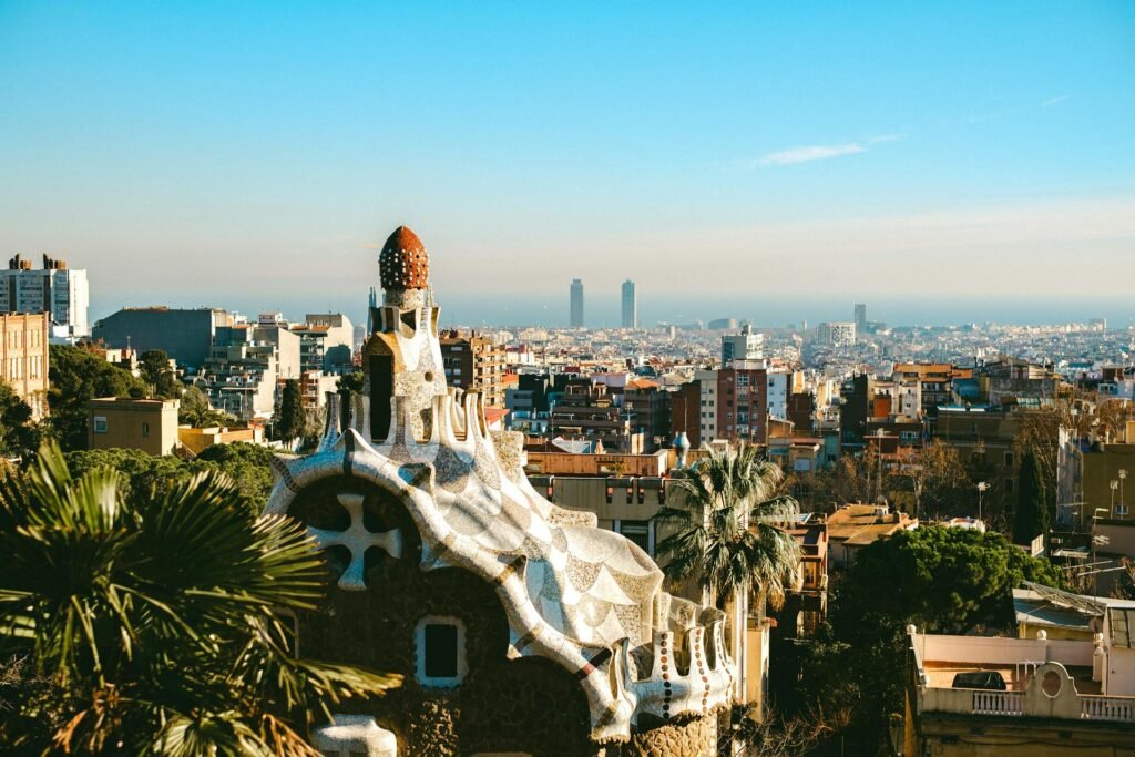 Aerial view of Park Güell's mosaic terrace with Barcelona cityscape and Mediterranean Sea in the background