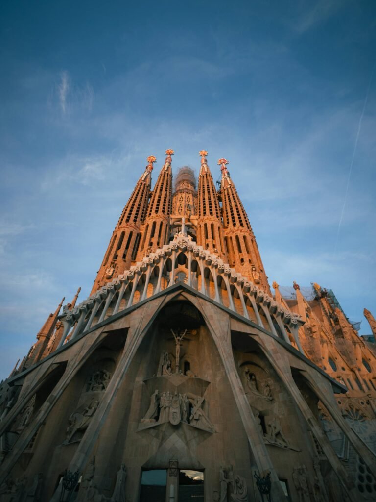 Sagrada Família facade bathed in sunrise warmth, displaying Gaudí's structure within urban Barcelona
