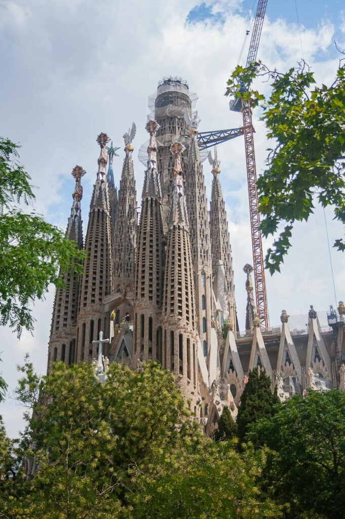 Wide perspective showing Sagrada Família's intricate architecture set within Barcelona's sunny urban environment