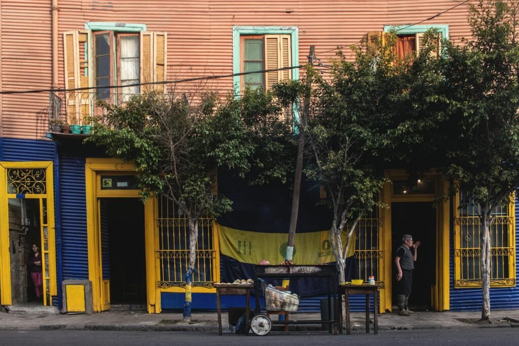 Vibrant street scene of La Boca neighborhood with the famous El Caminito's brightly colored corrugated-iron houses — the working-class barrio painted with leftover ship paint by Argentine artist Quinquela Martín