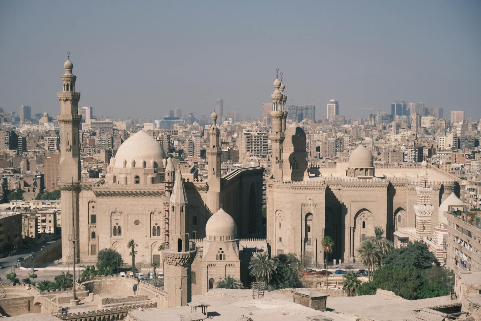 Aerial view of historic Cairo's Islamic skyline with the Mosque-Madrasa of Sultan Hassan rising above the densely built old city