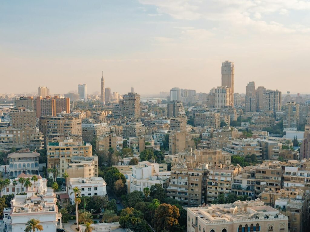 The modern Cairo skyline at dusk, with the Cairo Tower and high-rise buildings along the Nile catching the last light of day