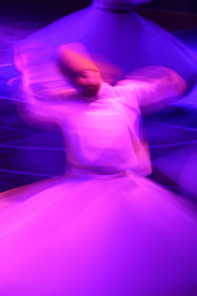 A tanoura performer mid-spin during a traditional Sufi whirling dance, with the colorful skirt extended in vibrant motion