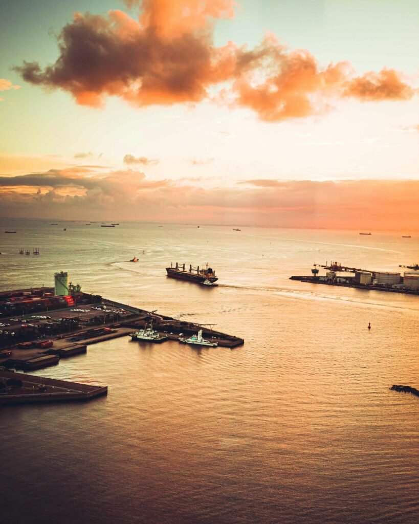 Aerial sunset view of Chiba Harbor on Tokyo Bay — cargo ships, the modern port complex, and the vivid Japanese east-coast sky capturing the city's role as a major industrial port