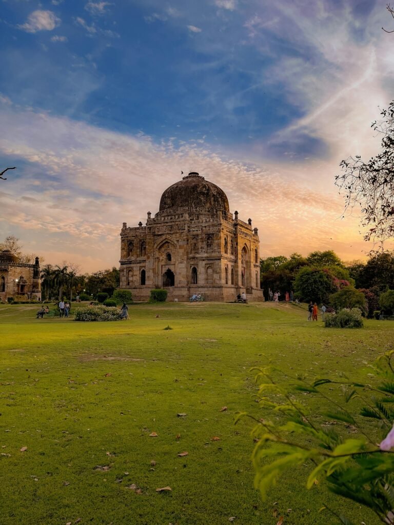 Historic Mughal-era tomb at Lodhi Gardens in New Delhi at sunset, vibrant sky and lush greenery