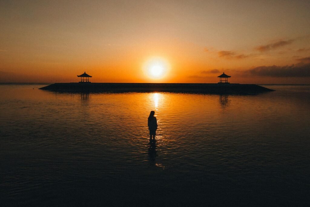 Tranquil Sanur Beach scene with traditional bale pavilions silhouetted at sunrise — South Denpasar district