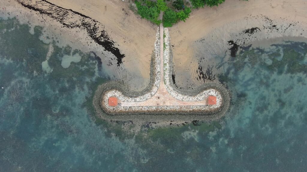 Drone shot capturing the unique stone pier and turquoise coastline of Sanur in southern Denpasar