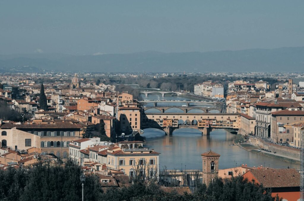 Stunning view of Florence featuring the iconic 1345 medieval Ponte Vecchio bridge with its goldsmith shops spanning the Arno River — the only Florence bridge to survive World War II bombing