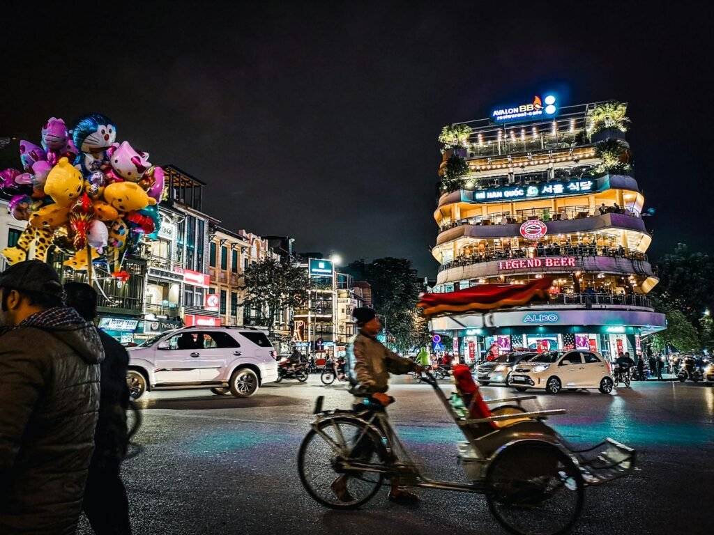 The bustling nightlife of Hanoi with colorful balloons, busy streets, and lively architecture — the Old Quarter's signature pedestrian-weekend evening atmosphere