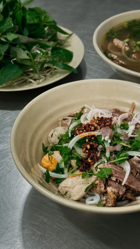 Bowl of traditional Vietnamese pho served with fresh herbs and spices, the iconic dish of Ho Chi Minh City cuisine
