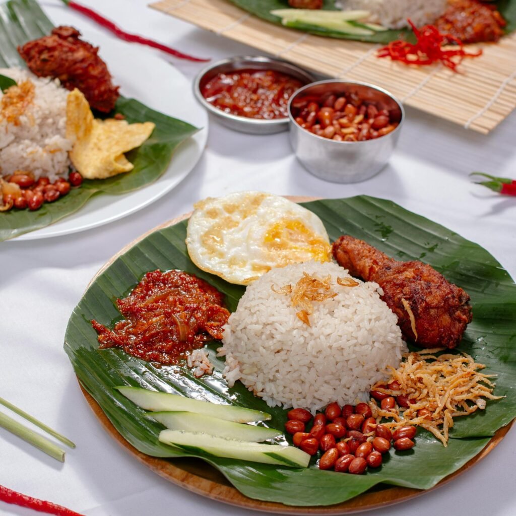 Delicious traditional Nasi Lemak — Malaysia's signature dish with coconut rice, fried chicken, sambal, and garnishes served on banana leaf