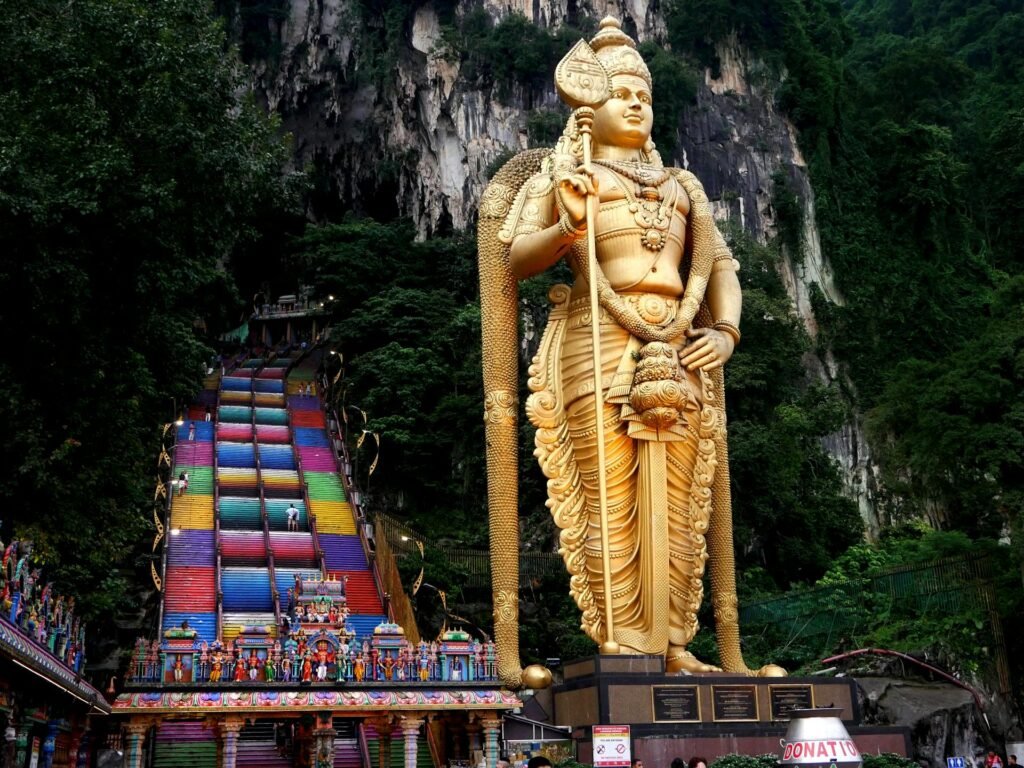 The 42.7-meter golden Lord Murugan statue at Batu Caves outside Kuala Lumpur, with the rainbow-colored 272-step staircase rising behind