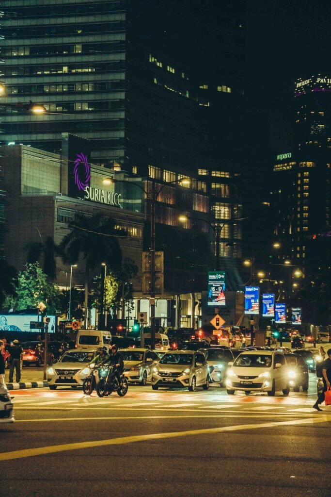 Cars and city lights on a Kuala Lumpur street at night near Suria KLCC, capturing the city's urban pulse