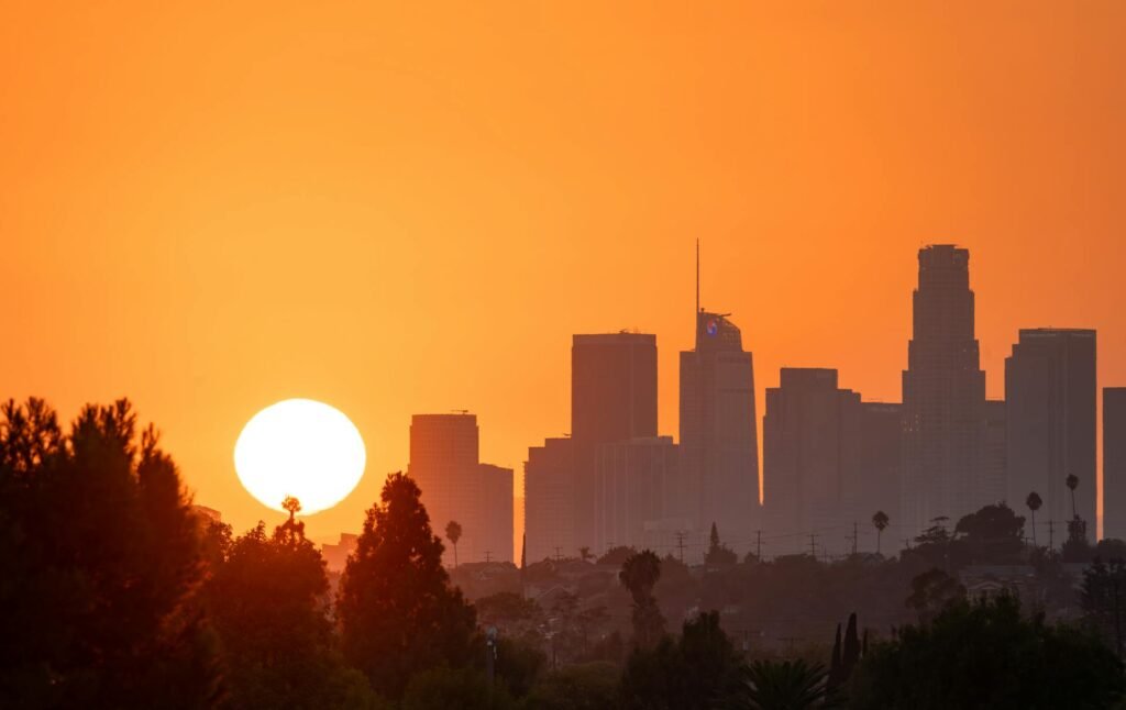 Bright orange sunset over downtown Los Angeles skyline with palm trees silhouetted