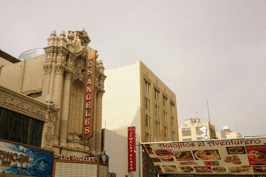 A vintage view of a historic Los Angeles theater with a bustling street market in the foreground