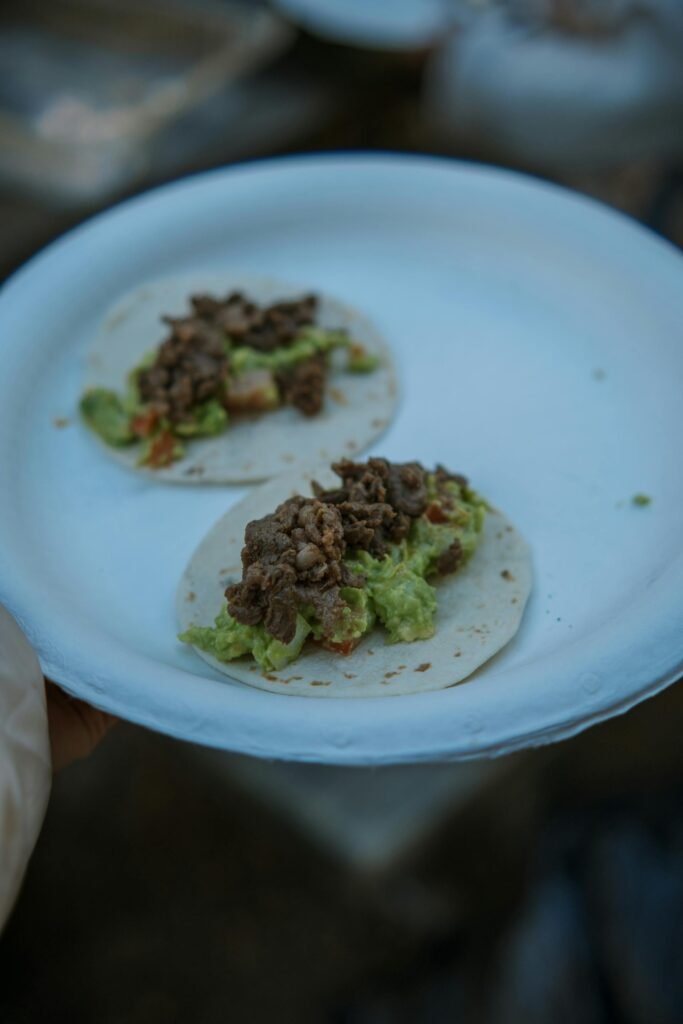 Two beef tacos with guacamole on a paper plate, the iconic LA street food experience