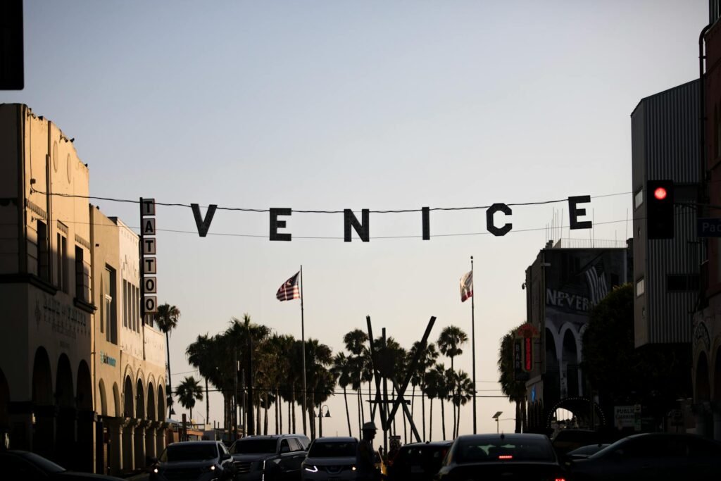 The iconic Venice Beach sign in Los Angeles at sunset with palm trees silhouetted