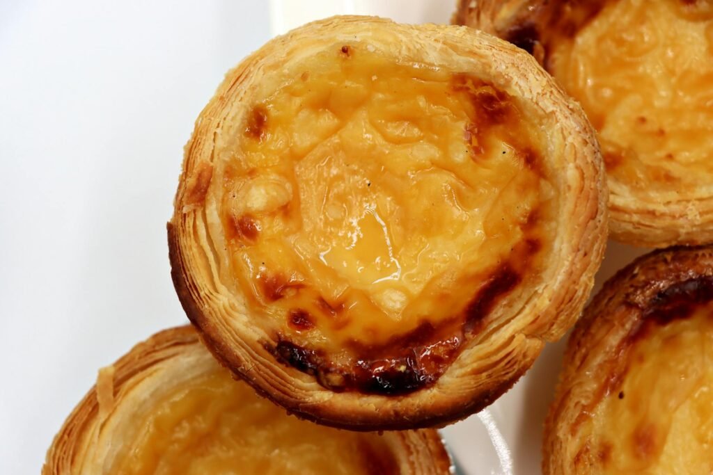 Close-up of traditional Portuguese custard tarts (pastel de nata), the iconic Macanese pastry adapted from Lisbon traditions