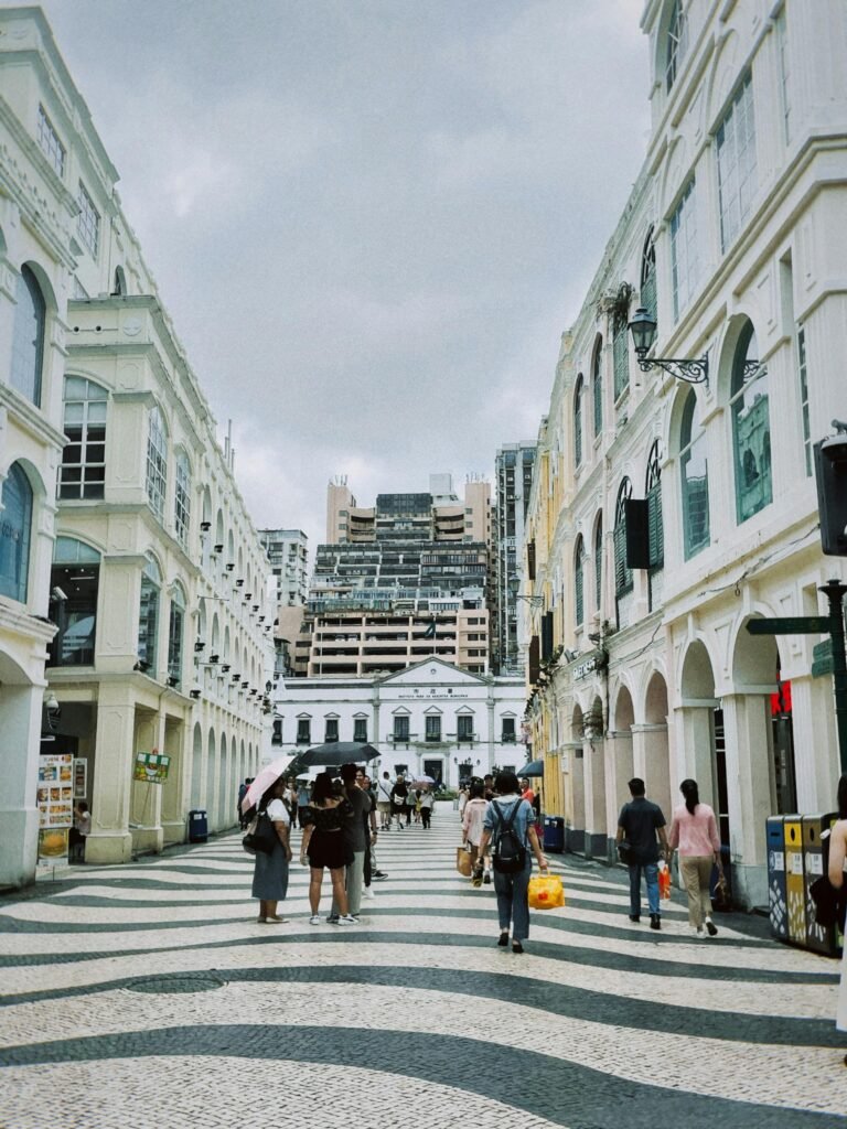 A street view in Taipa, Macau, with colonial architecture, pastel buildings, and pedestrians