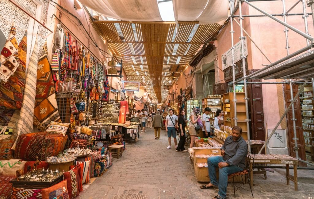 Vibrant colors and lively atmosphere of a Marrakech souk — the warren of covered alleys north of Jemaa el-Fnaa where the city's leather, brass, textile, and spice trades unfold