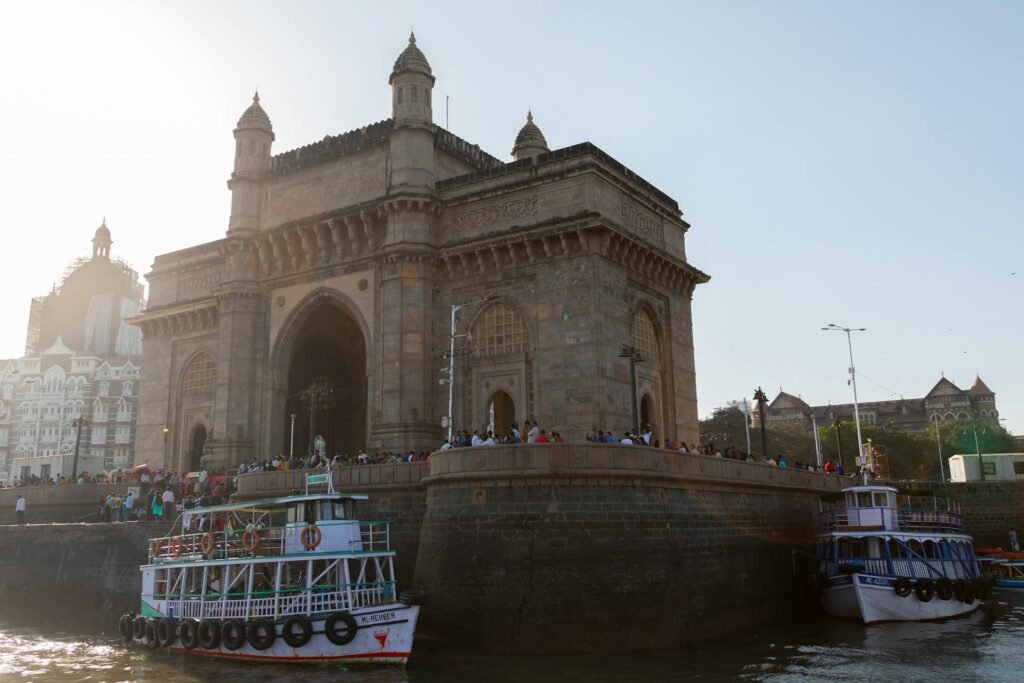 The Gateway of India at sunset with traditional boats and visitors gathering by the Arabian Sea in Mumbai