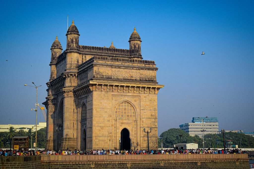 The Gateway of India in Mumbai under a clear blue sky, the iconic 1924 stone archway commemorating King George V's visit