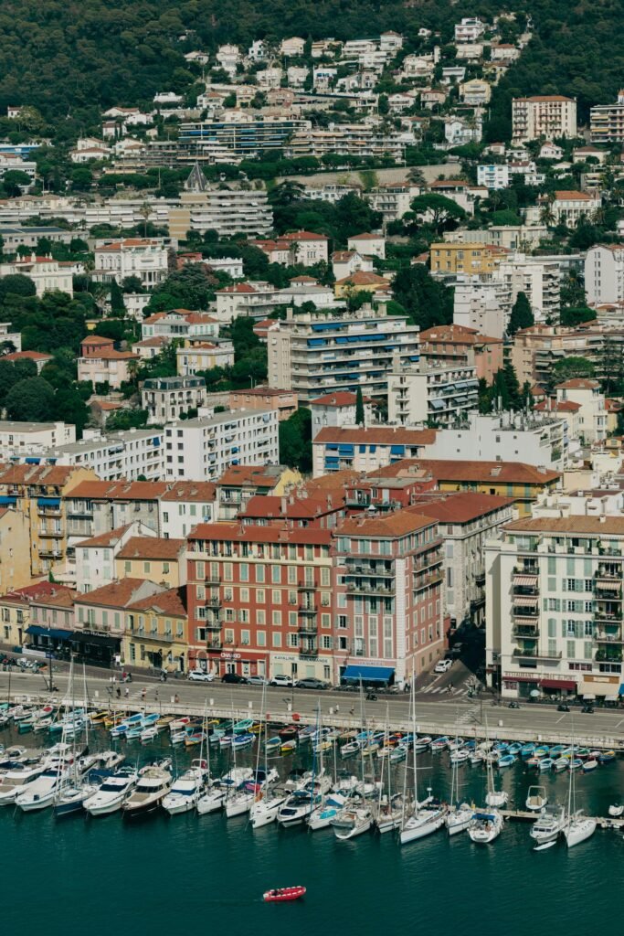 Stunning aerial view of Nice harbor in France — yachts moored at Port Lympia with the colorful buildings of the Old Town and the Mediterranean coastline framing the working port